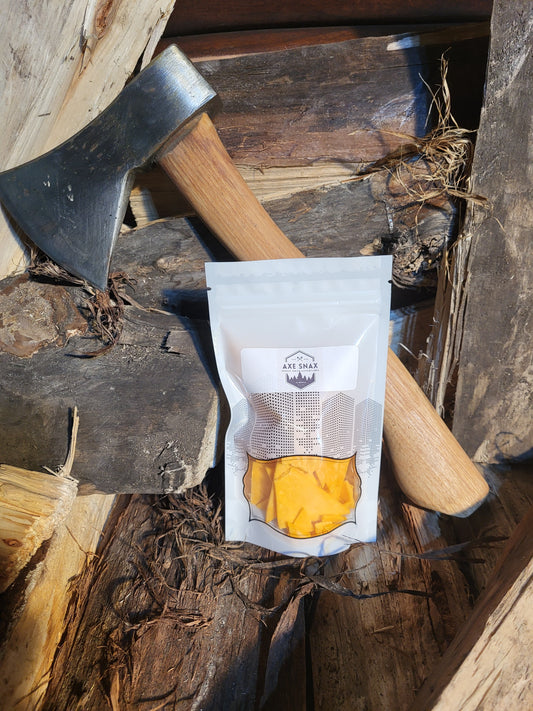 Packaged freeze dried cheddar cheese on a wooden background with an axe